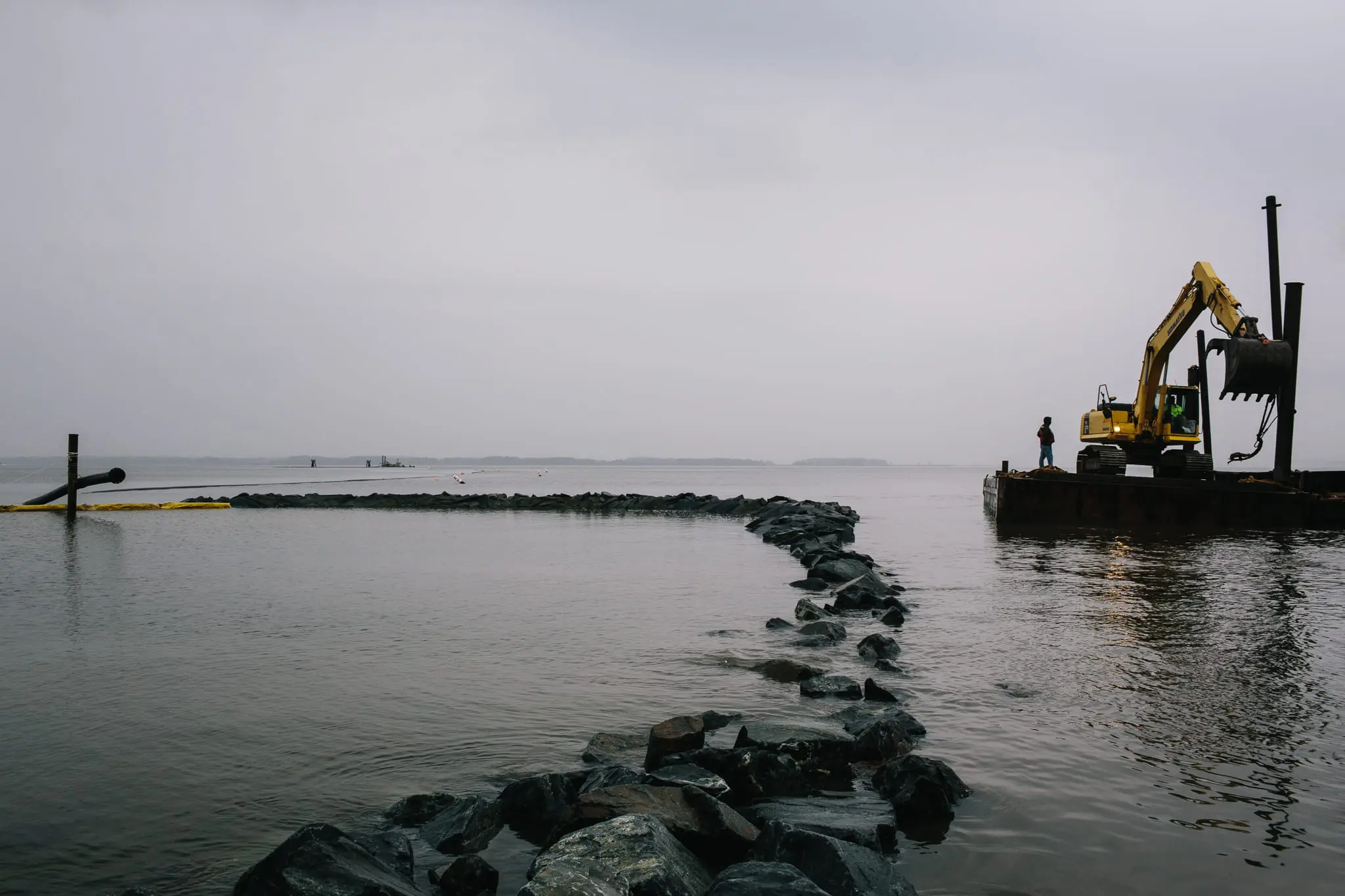 Workers pump sand to construct a living shoreline.
