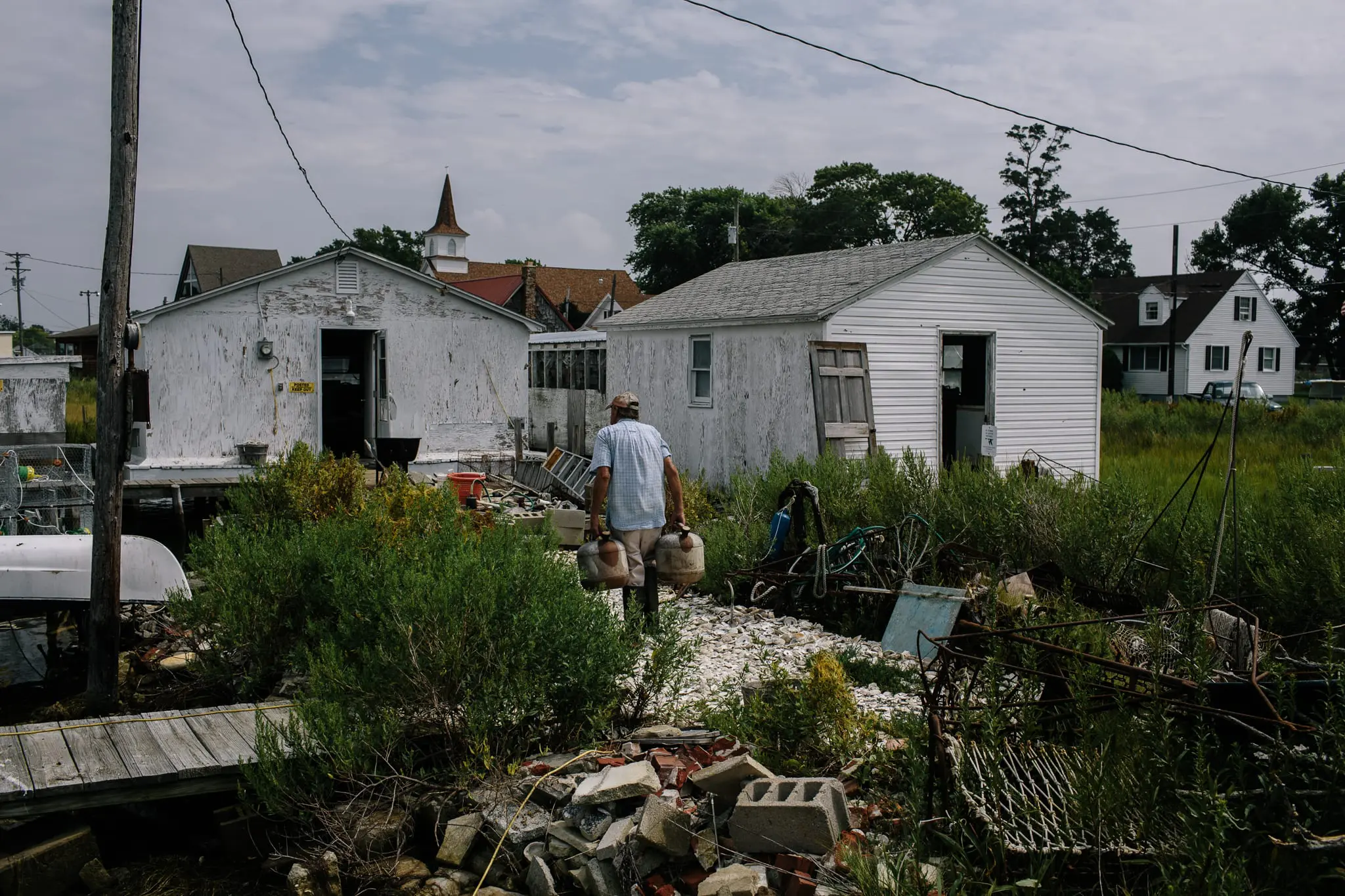 A waterman carries gas cans to his crab shack.